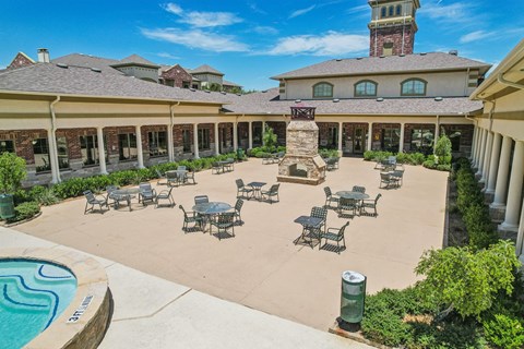 A large outdoor patio area with tables and chairs and a pool.