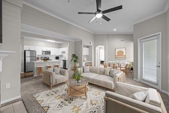 a living room with couches and chairs and a ceiling fan