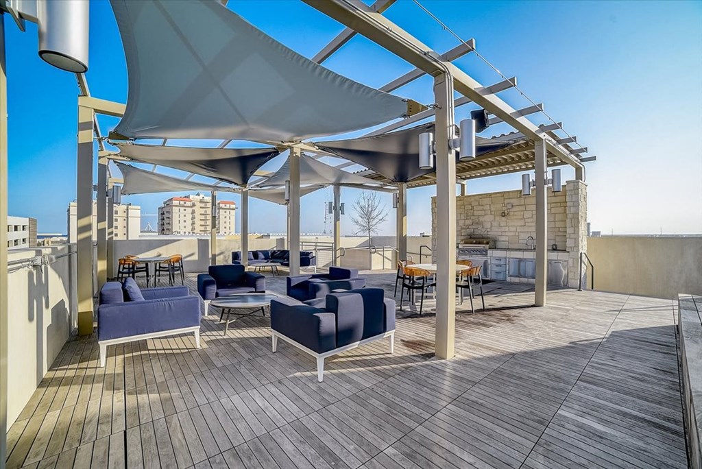 a roof deck with blue couches and chairs and a patio