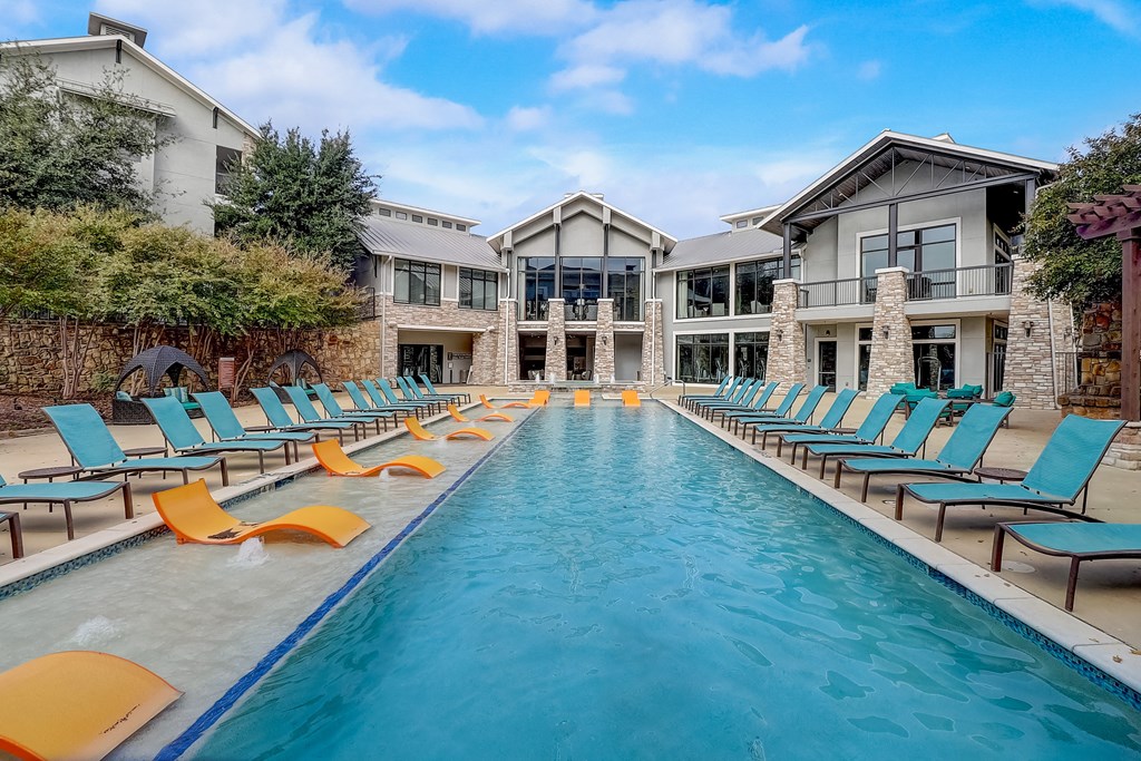 a swimming pool with yellow and blue chairs in front of a house