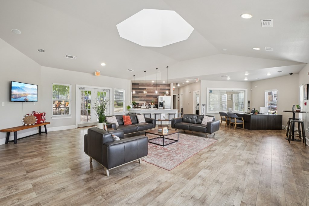 A spacious living room with a variety of seating options and a flat-screen TV mounted on the wall.