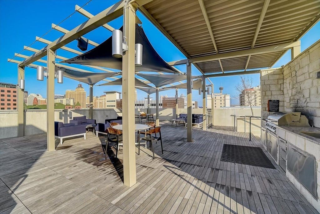 a rooftop patio with a grill and a view of the city