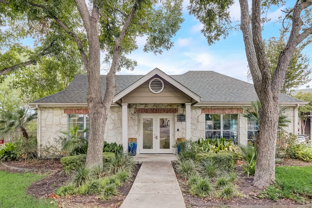 a white house with trees and a sidewalk in front of it