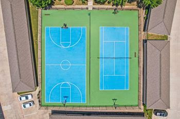 Two blue tennis courts surrounded by green grass.