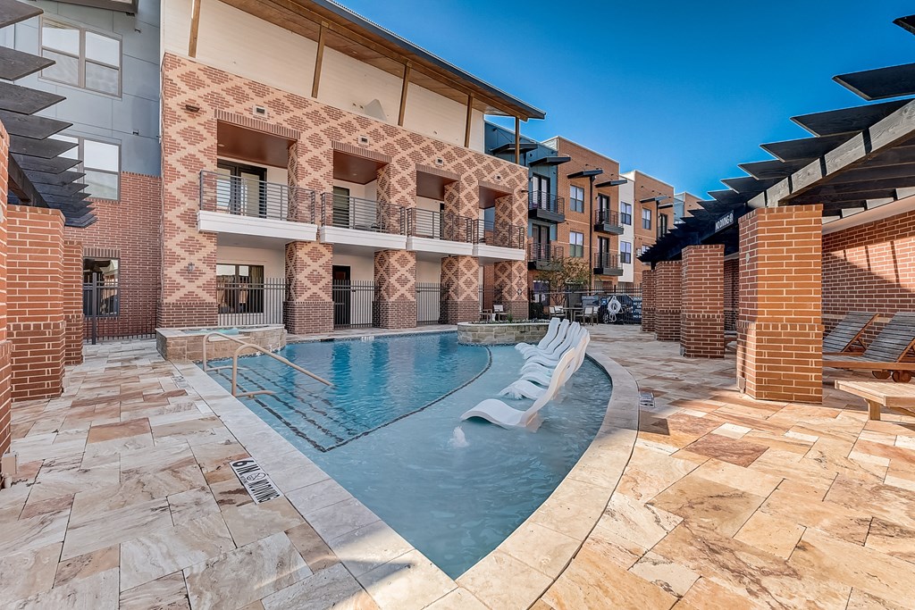 a swimming pool with two chairs in front of a building