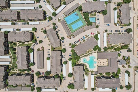 A bird's eye view of a residential area with houses, cars, and a swimming pool.