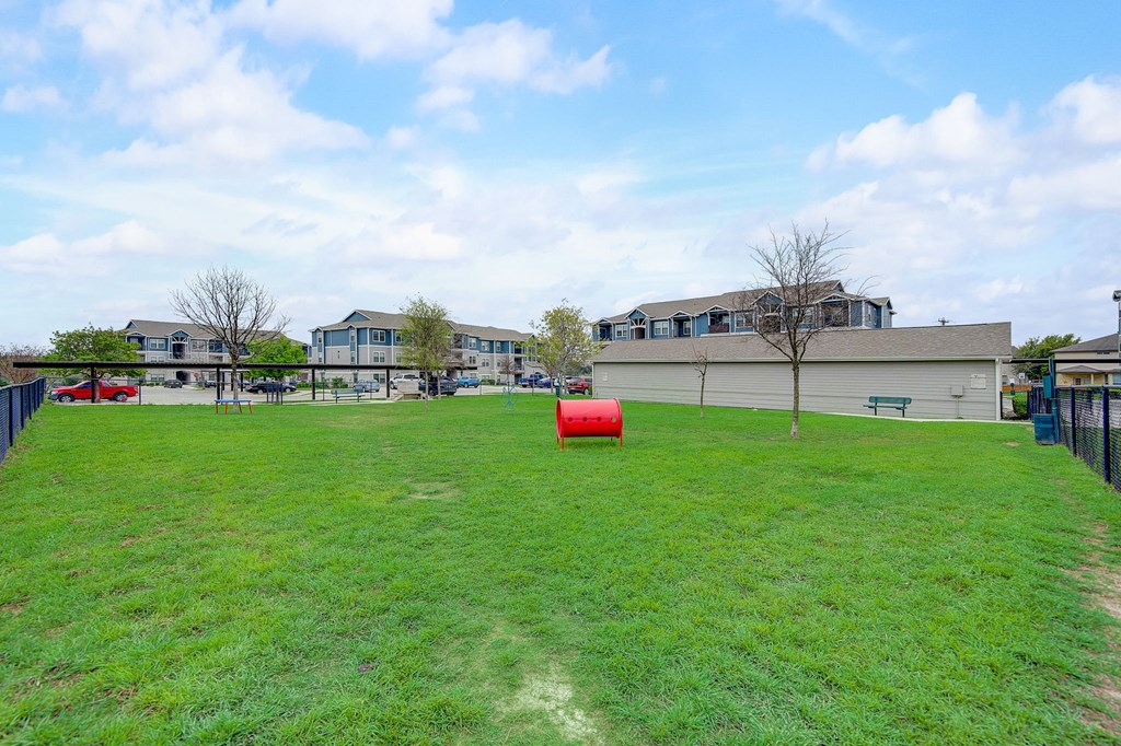 the backyard has a large grass field with a red cylinder in the middle