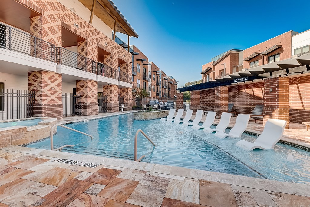 a swimming pool with chairs in front of a building