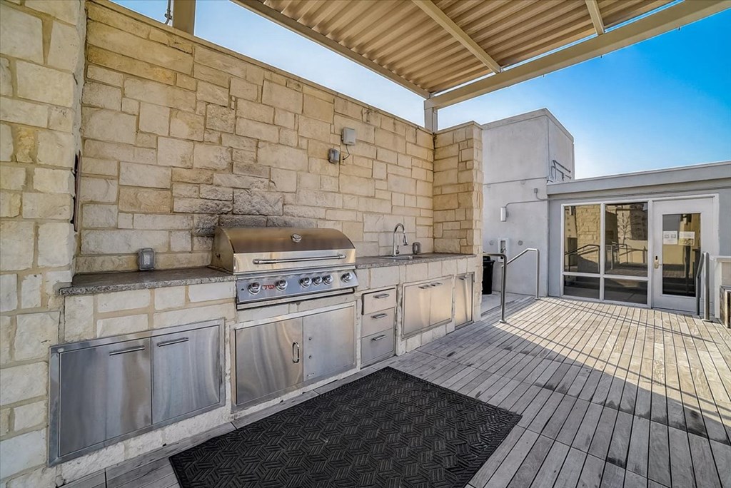 the outdoor kitchen has stainless steel appliances and a grill