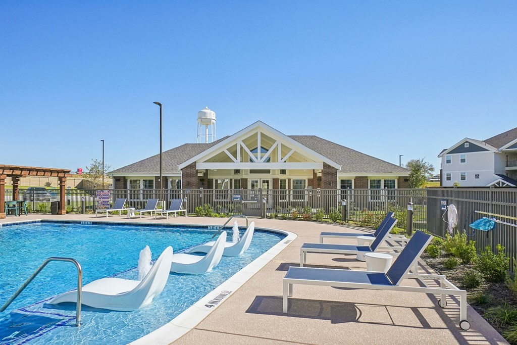 A pool with lounge chairs and a building in the background.