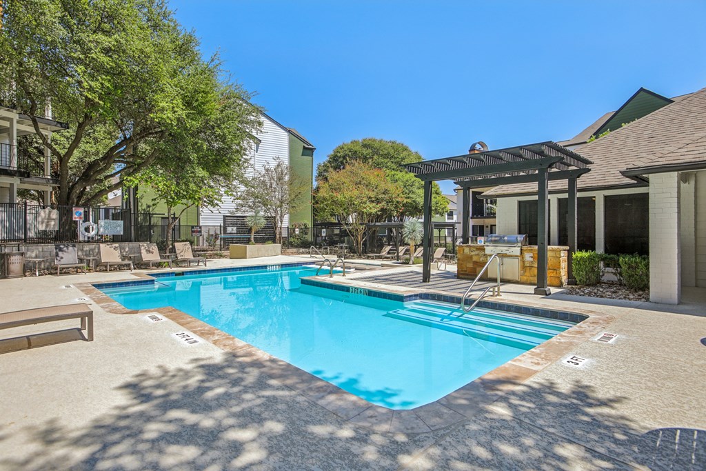 A large outdoor swimming pool surrounded by trees and a building.