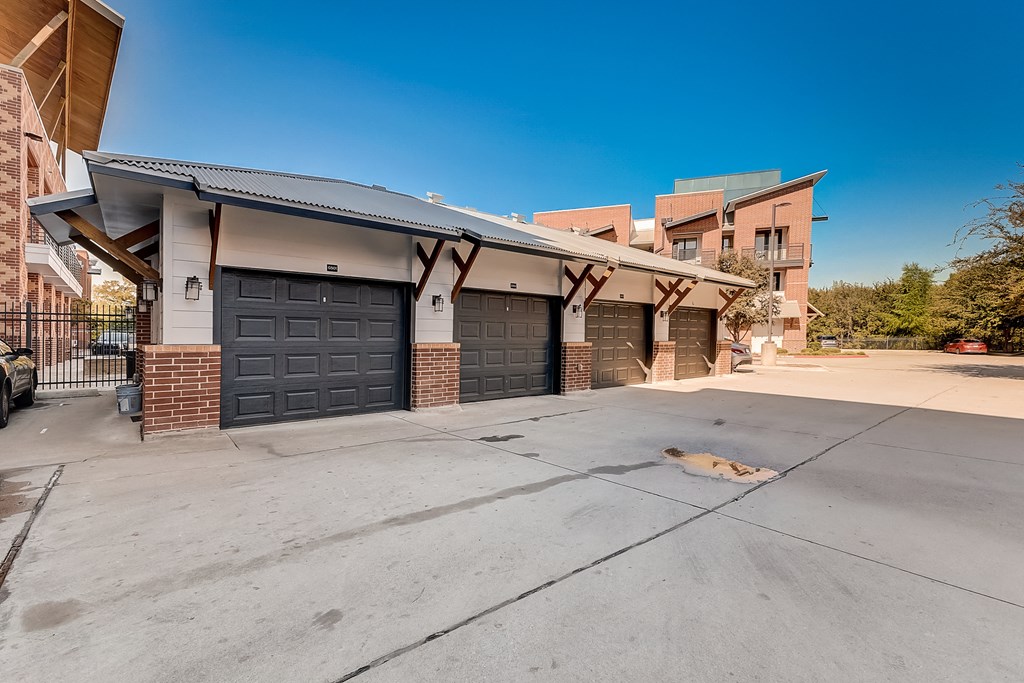 a garage with two black doors and a building in the background
