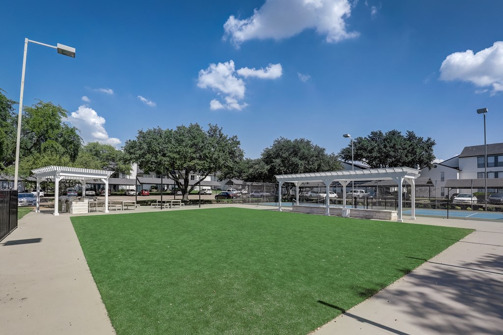 a park with a green lawn and some shade structures