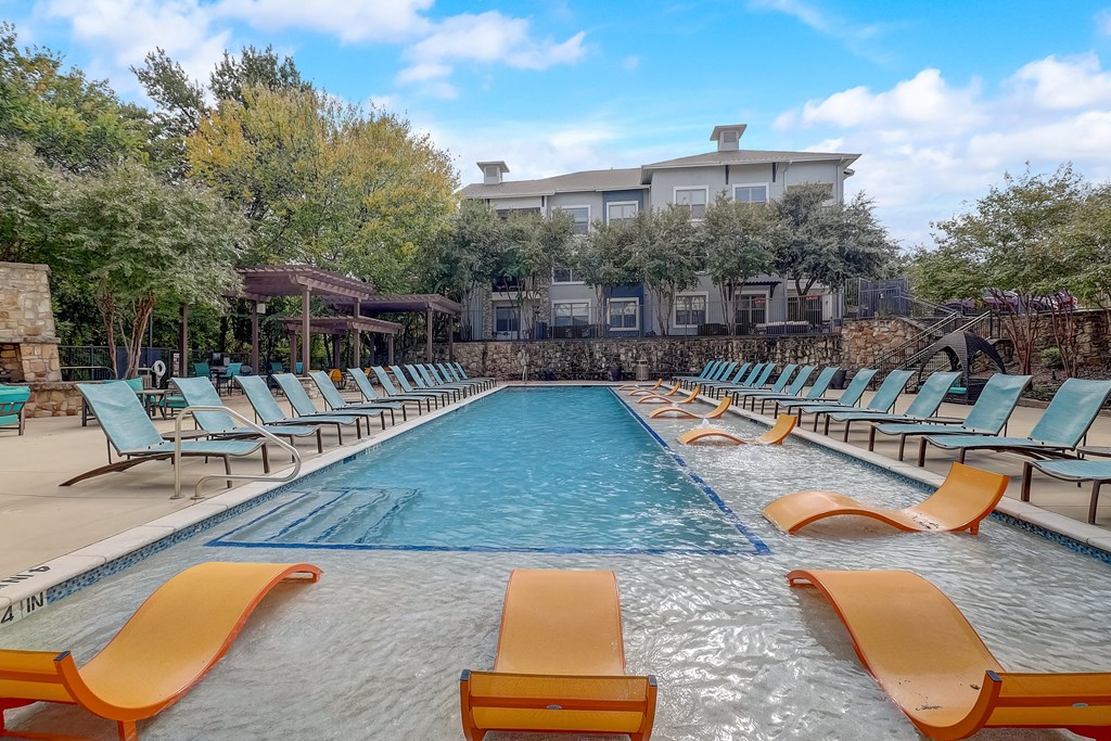 a swimming pool with chairs and a building in the background