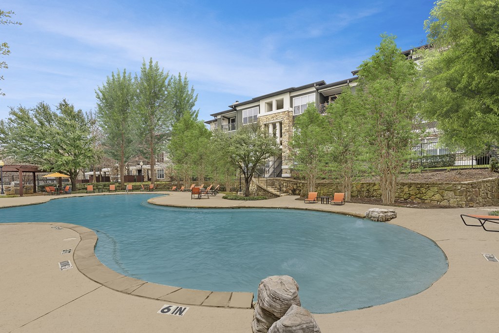 a swimming pool with trees and a building in the background
