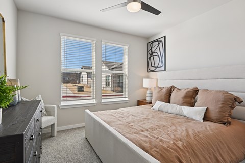 A bedroom with a large bed and a ceiling fan.
