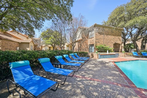 A pool surrounded by blue lounge chairs.