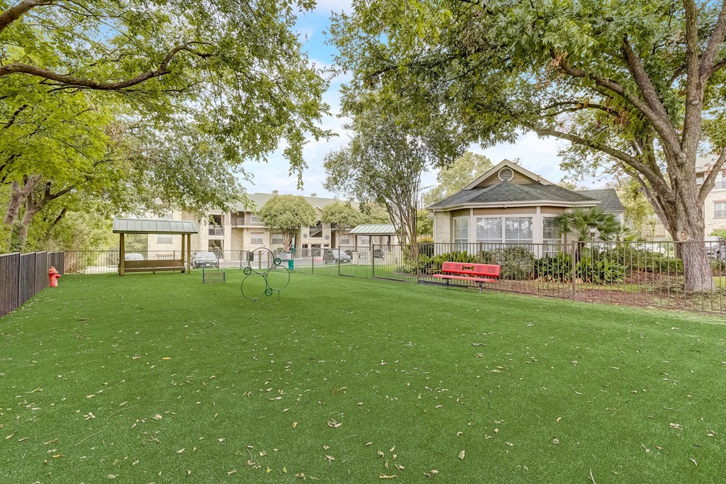a park with a red bench in front of a house