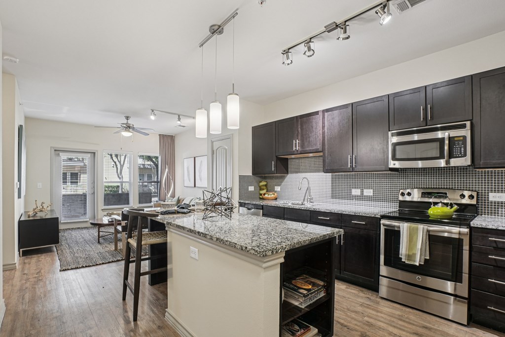 A modern kitchen with dark wood cabinets and stainless steel appliances.