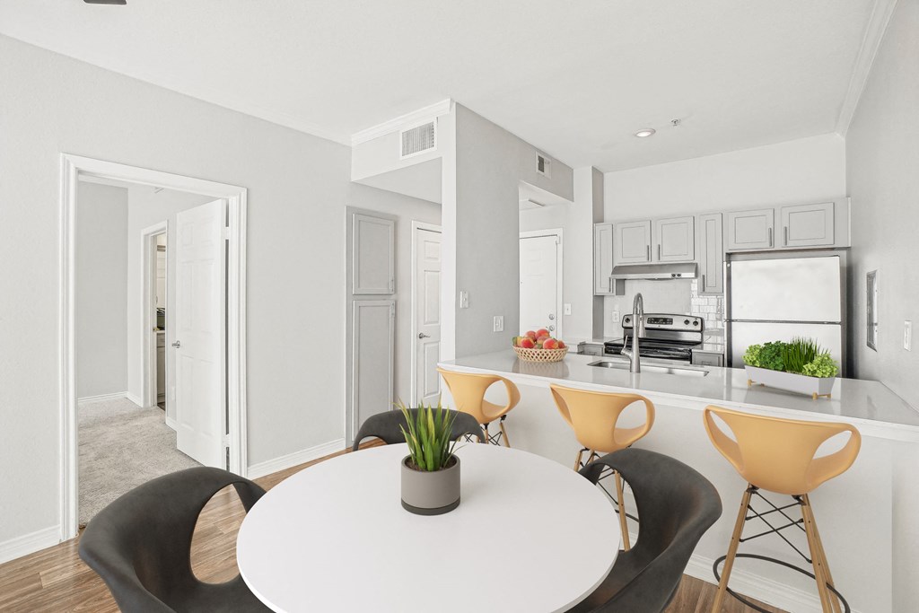 A white dining table with a potted plant on it and four chairs around it.