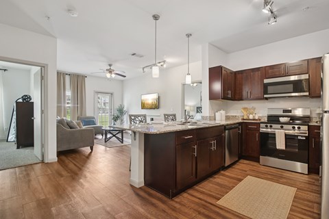 A modern kitchen with dark wood cabinets and stainless steel appliances.
