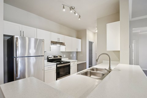 A modern kitchen with a stainless steel refrigerator and a sink.