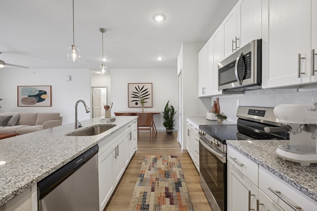 A modern kitchen with white cabinets and granite countertops.