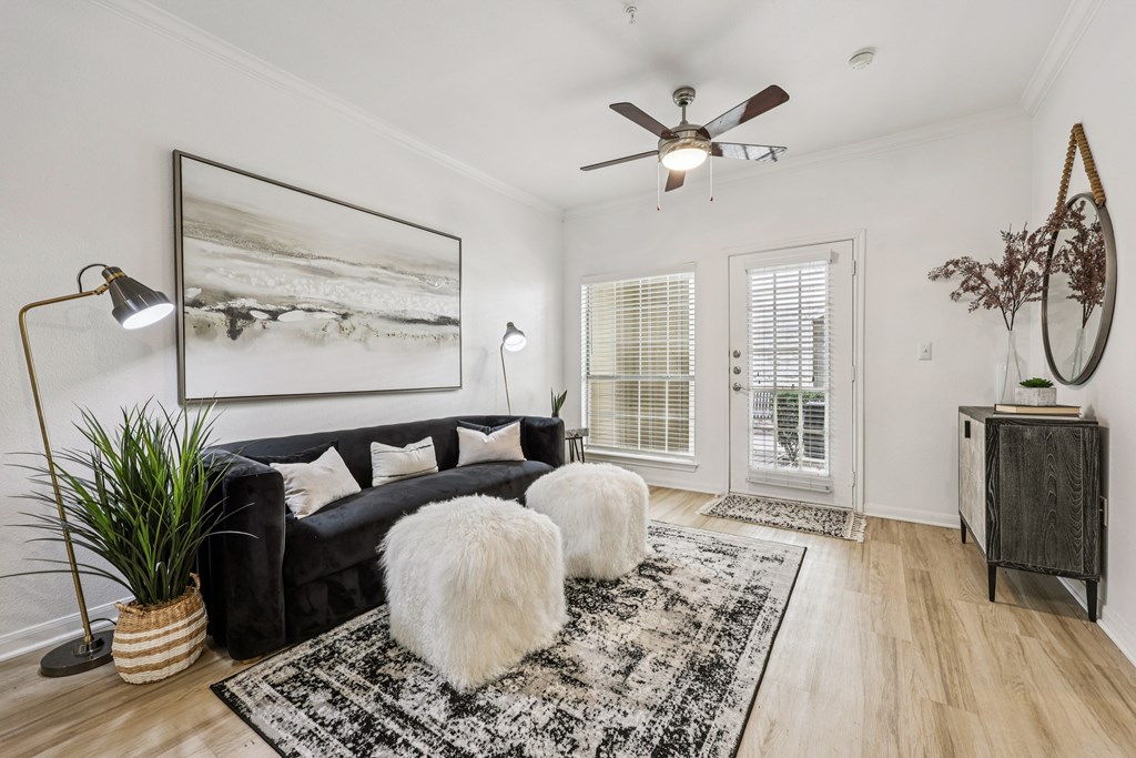 A living room with a black couch, a rug, and a ceiling fan.