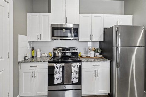 A modern kitchen with a stainless steel refrigerator, microwave, and oven.