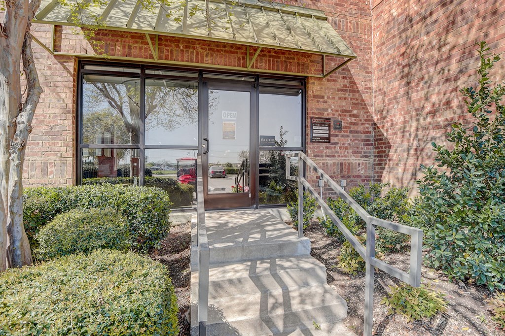 the entrance to a brick building with a staircase and glass doors