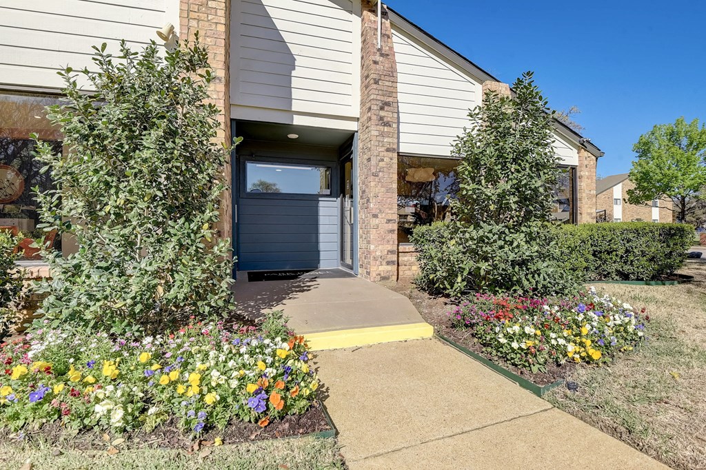 a sidewalk in front of a house with a flower garden