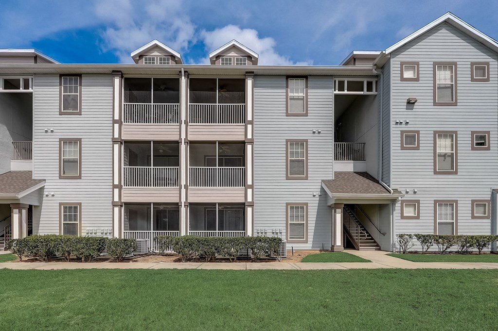 an apartment building with balconies and a grass yard