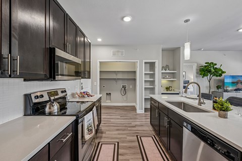 A modern kitchen with dark wood cabinets and stainless steel appliances.