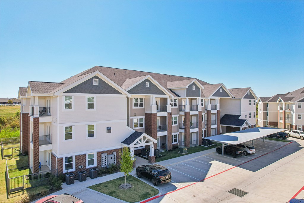 A large apartment complex with a parking lot in front.