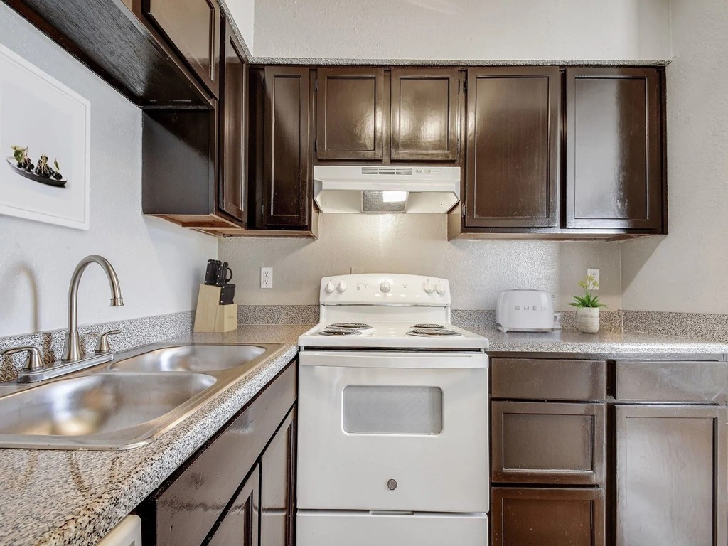 A kitchen with a white stove and brown cabinets.
