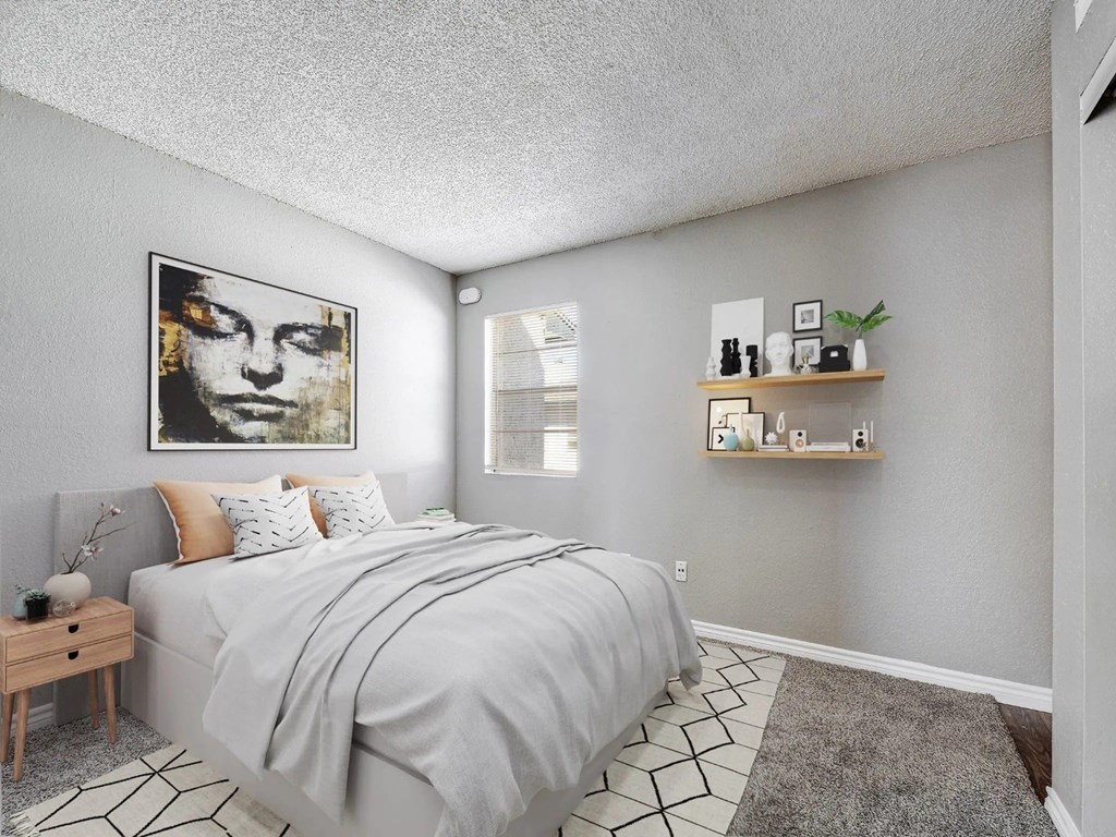 A bedroom with a bed, nightstand, and a painting on the wall.