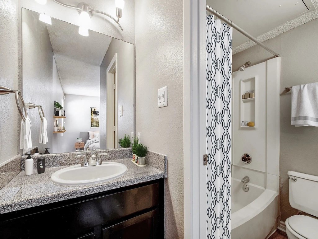 A bathroom with a sink, mirror, and shower.