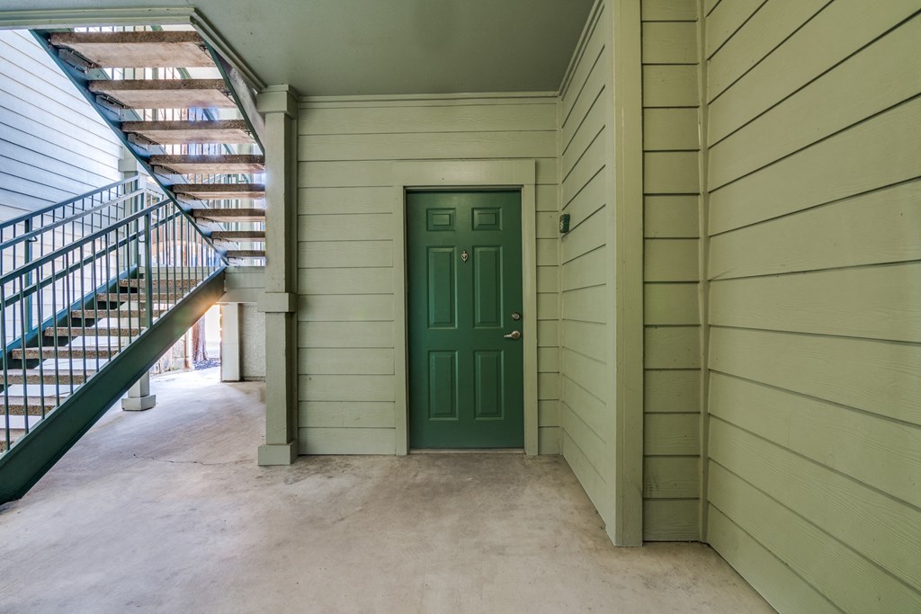 the entrance to a building with a green door and a staircase