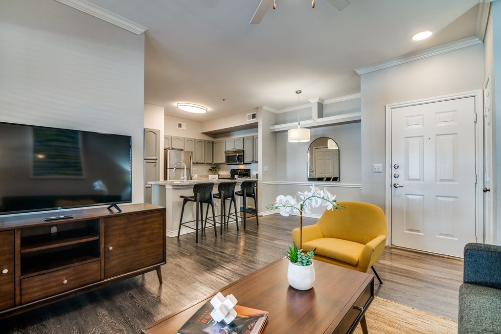 a living room with a tv and a kitchen in the background