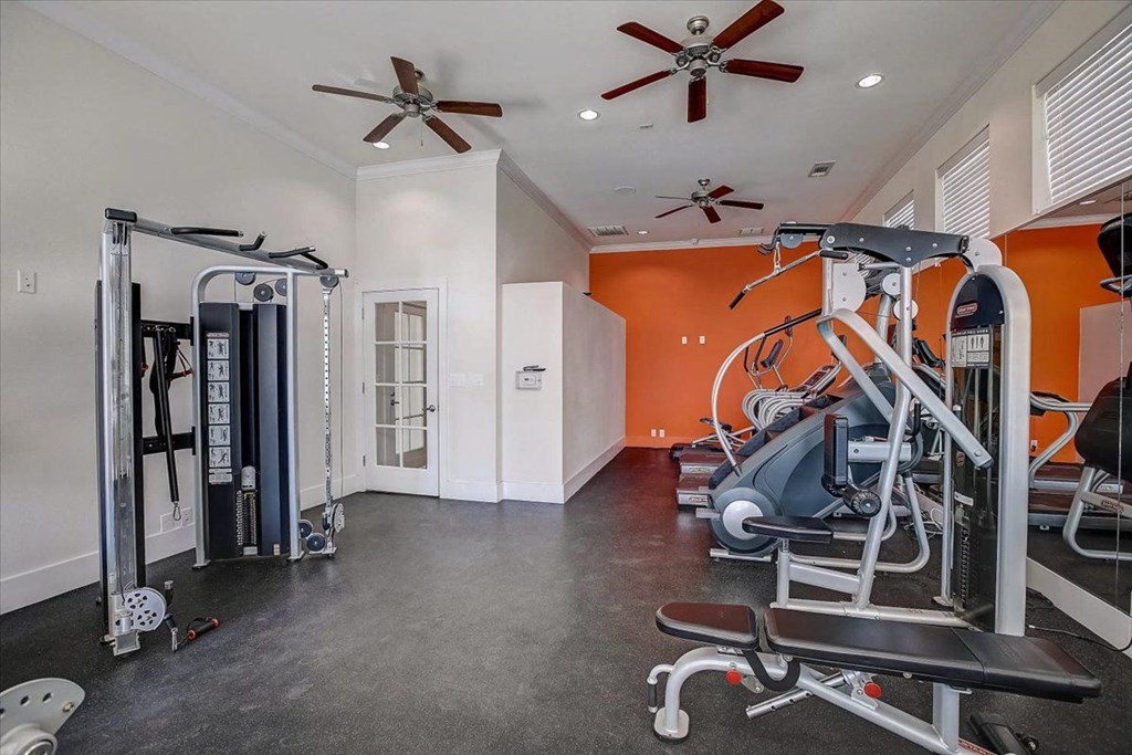 a gym with exercise equipment and ceiling fans