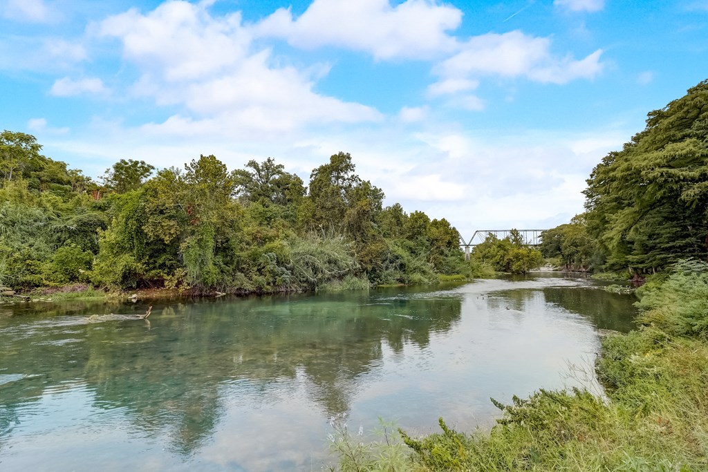 a river with trees on either side and a bridge in the background