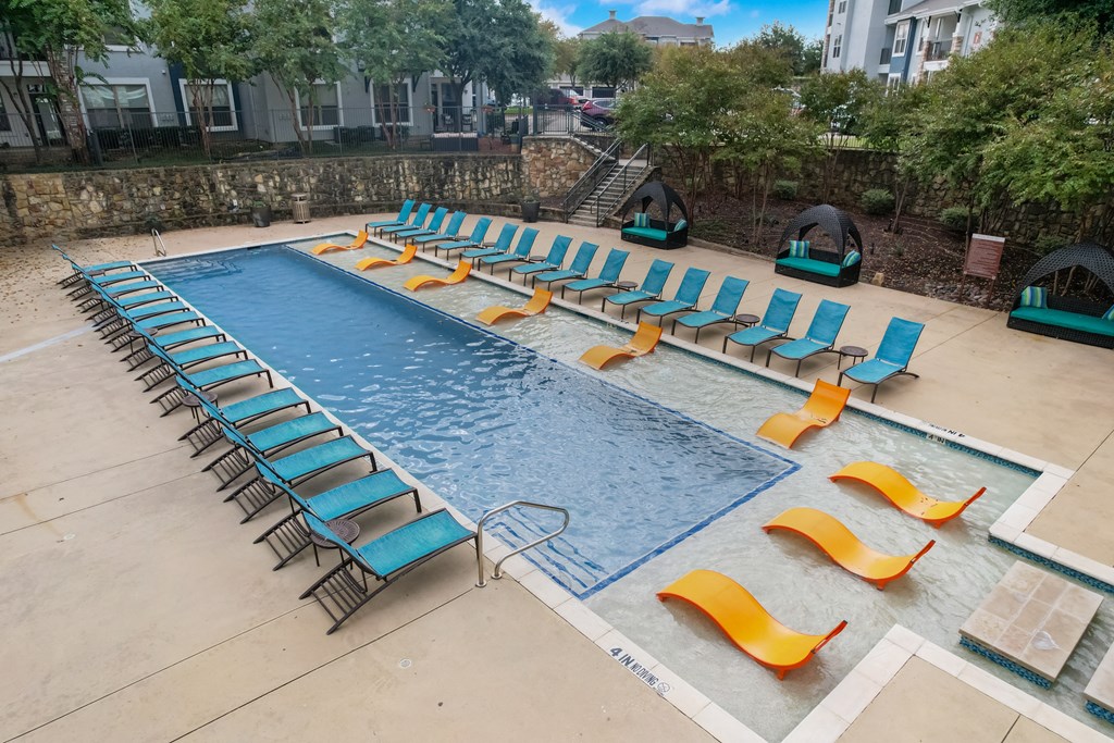 a swimming pool with lounge chairs and chairs around it