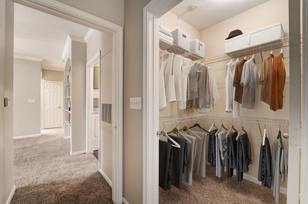 a walk in closet with a mirrored closet door and a closet full of clothes