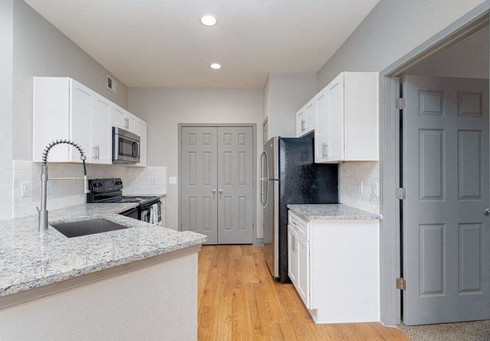 a kitchen with white cabinets and a sink and a refrigerator