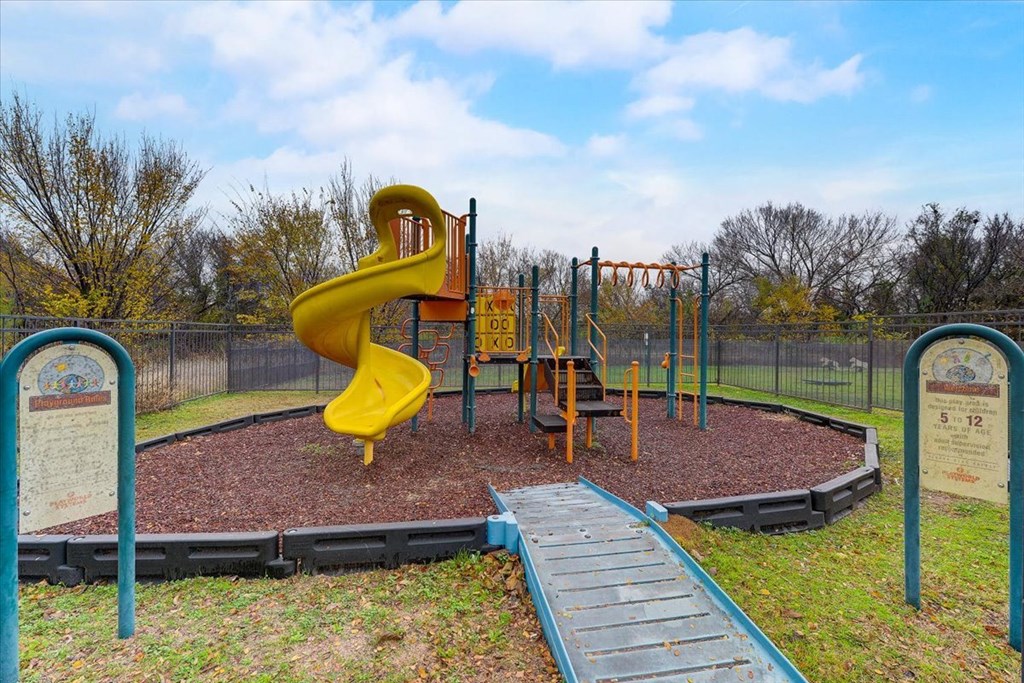 a playground with a yellow slide in a park