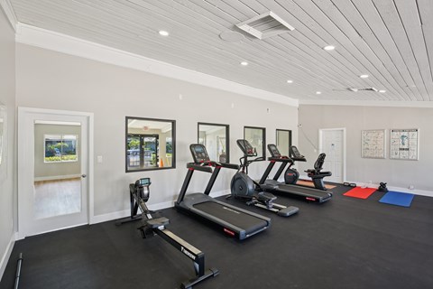 A spacious gym with treadmills, exercise bikes, and yoga mats.