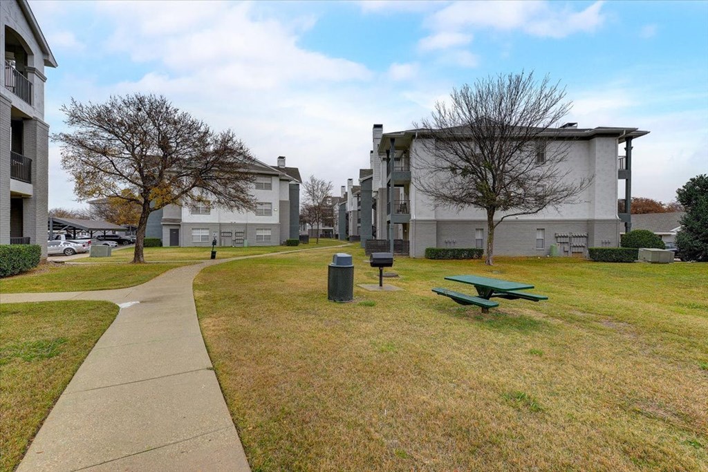 a park with a green picnic table and a sidewalk