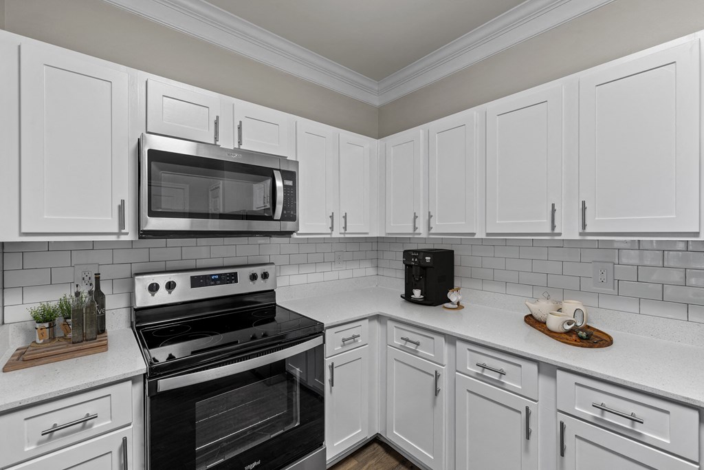 a kitchen with white cabinets and black appliances and a microwave