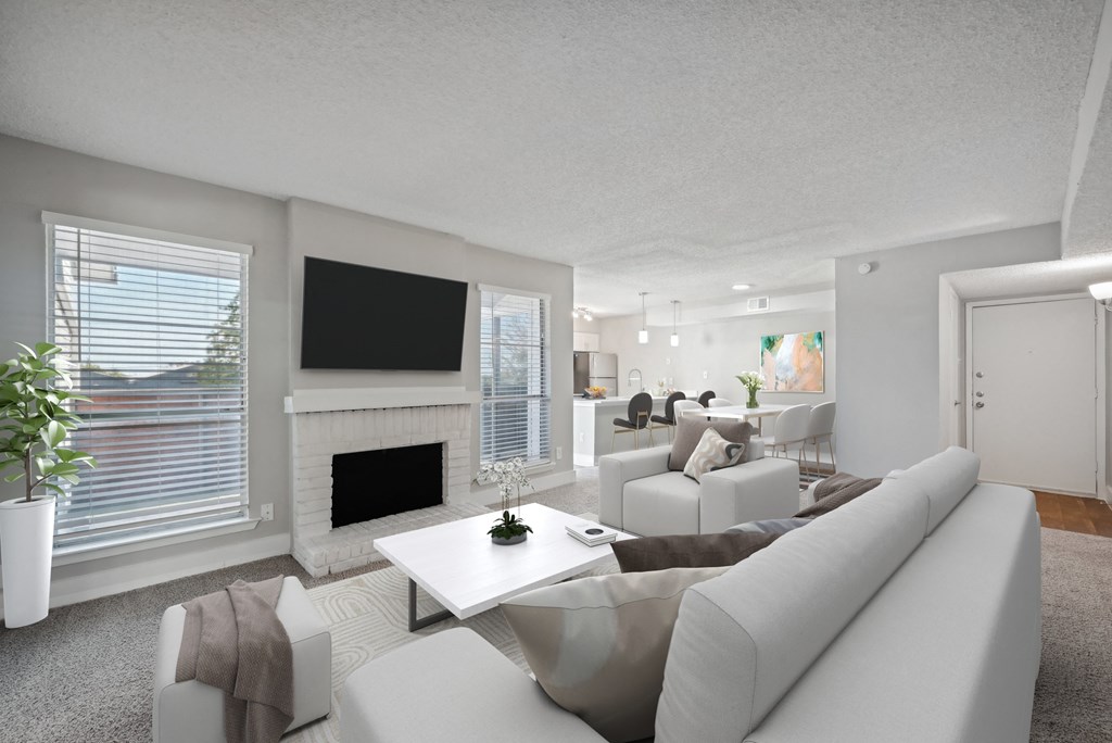 a living room with white couches and chairs and a fireplace