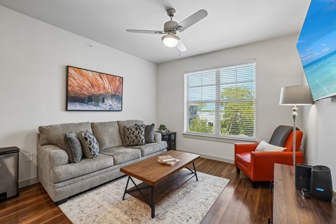 A living room with a grey couch, a red chair, a coffee table, and a painting on the wall.